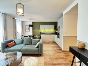 A modern living room with a grey sofa, a glass coffee table, and a wooden floor.