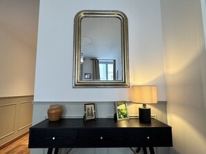 Une console en bois foncé, agrémentée d’un miroir, d’un vase et d’une lampe.
