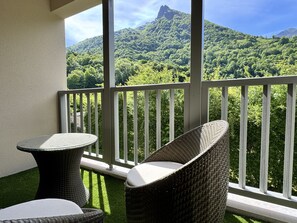 A balcony with wicker furniture and a view of a lush green mountain. - Bel apt 85m2 8P. Parking. Balcon (Cauterets)