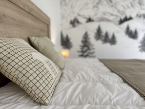 A bed with white bedding and patterned pillows, a wooden headboard, and a wall with a mountain landscape mural. - Bel apt 85m2 8P. Parking. Balcon (Cauterets)