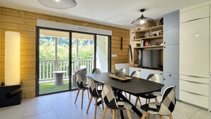 Une cuisine moderne avec un coin repas, dotée d’une grande fenêtre, d’un téléviseur encastré et d’un mur d’accent en bois.