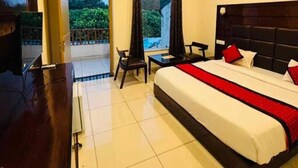 Une chambre d’hôtel avec un grand lit, un bureau, une chaise et un téléviseur.