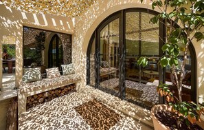 Un interior luminoso con zona de estar, un amplio ventanal de arco y una planta en maceta.