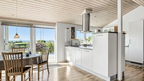 A modern kitchen with a large island, white cabinetry, and a view of the ocean.
