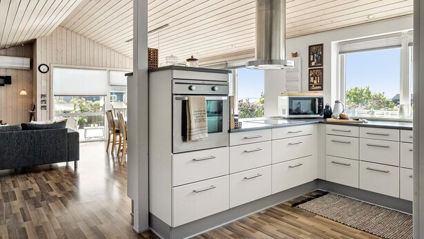A modern kitchen with white cabinets, stainless steel appliances, and a large window offering a view of the outdoors.