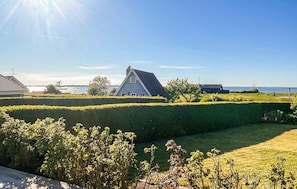 A rural landscape with a house, a body of water, and a clear sky.