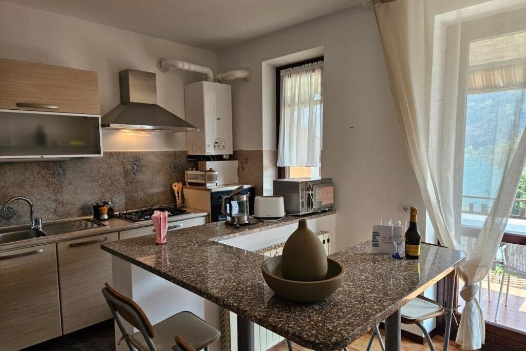 A modern kitchen with granite countertops, stainless steel appliances, and a large island with a bowl.