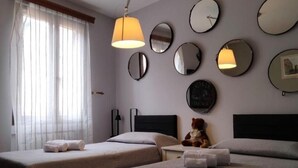 A hotel room with two beds, a teddy bear on the right bed, and multiple round mirrors on the wall.
