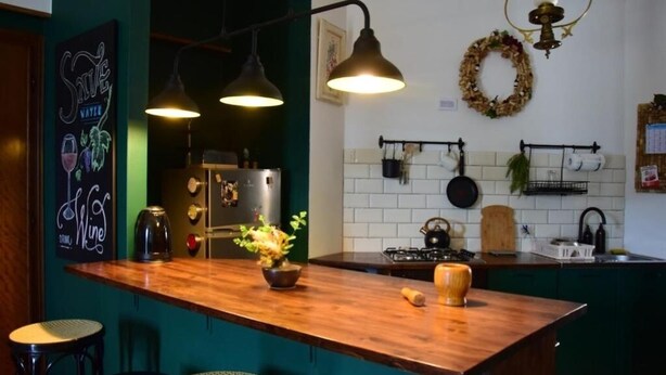 A kitchen with a wooden island, pendant lights, a refrigerator, and a stove.
