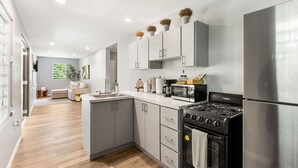 Una cocina moderna con armarios grises, un refrigerador de acero inoxidable, una estufa negra y un microondas.
