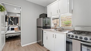 Una cocina compacta equipada con refrigerador, microondas, estufa y lavamanos.