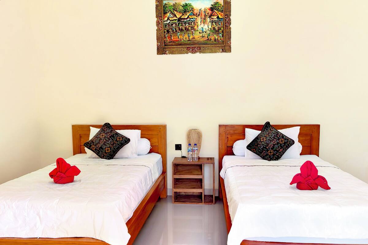 Una camera d'albergo con due letti in legno, biancheria da letto bianca e cuscini decorativi.
