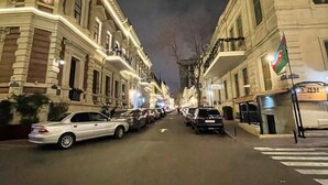 A street view at night with buildings on either side, a pedestrian crossing, and parked cars. - Central Budget GH  (Baku)