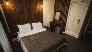 A bedroom with a large bed, a nightstand, a dresser, a mirror, and a door. - Central Budget GH  (Baku)
