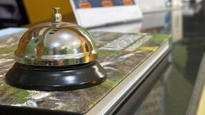 A reception desk with a glass-top counter and a bell. There are informational posters on the wall behind the counter. - Central Budget GH  (Baku)