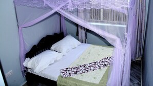 Una cama con dosel y ropa de cama blanca.