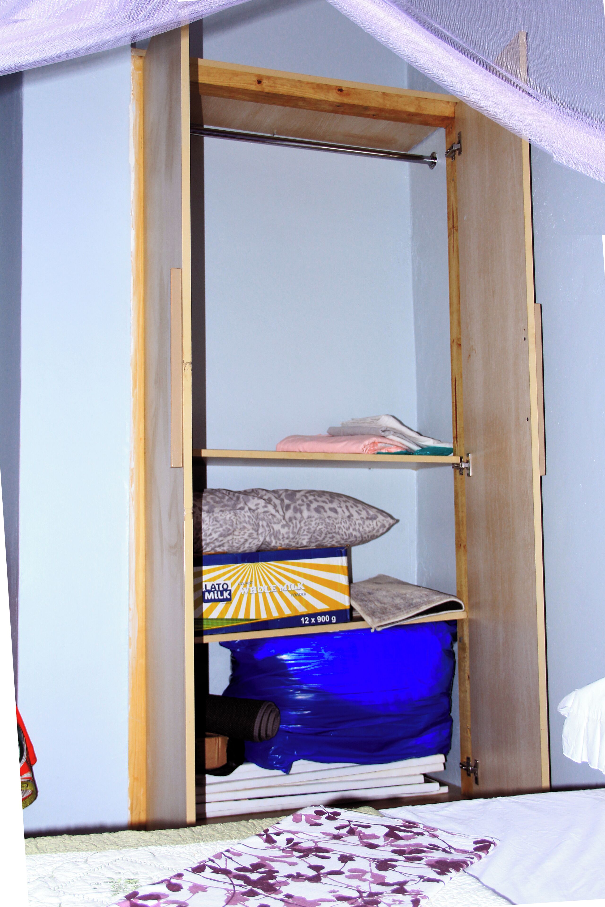 A wooden wardrobe with a blue storage bin and a leopard print pillow.