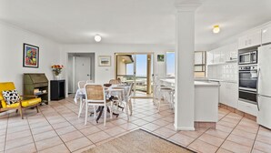 A modern apartment with a dining area, kitchen, and balcony. - Shelly Vista - Beach Days and Poolside Afternoons (East Ballina)