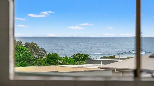 A view of the ocean from a window, with a clear sky and some greenery in the foreground. - Shelly Vista - Beach Days and Poolside Afternoons (East Ballina)