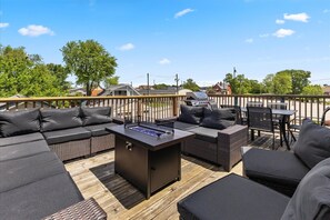 Une terrasse extérieure avec un barbecue, un espace salon et une vue sur le quartier.