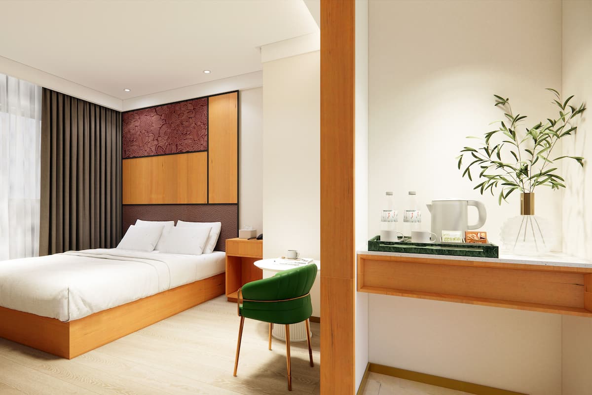 Quarto de hotel moderno com uma cama grande, uma escrivaninha com cadeira, uma cafeteira e um vaso com plantas.