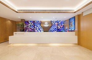 A reception desk with a modern design, a digital screen, and a decorative wall with leaf patterns. - Floral Hotel (Shanghai)