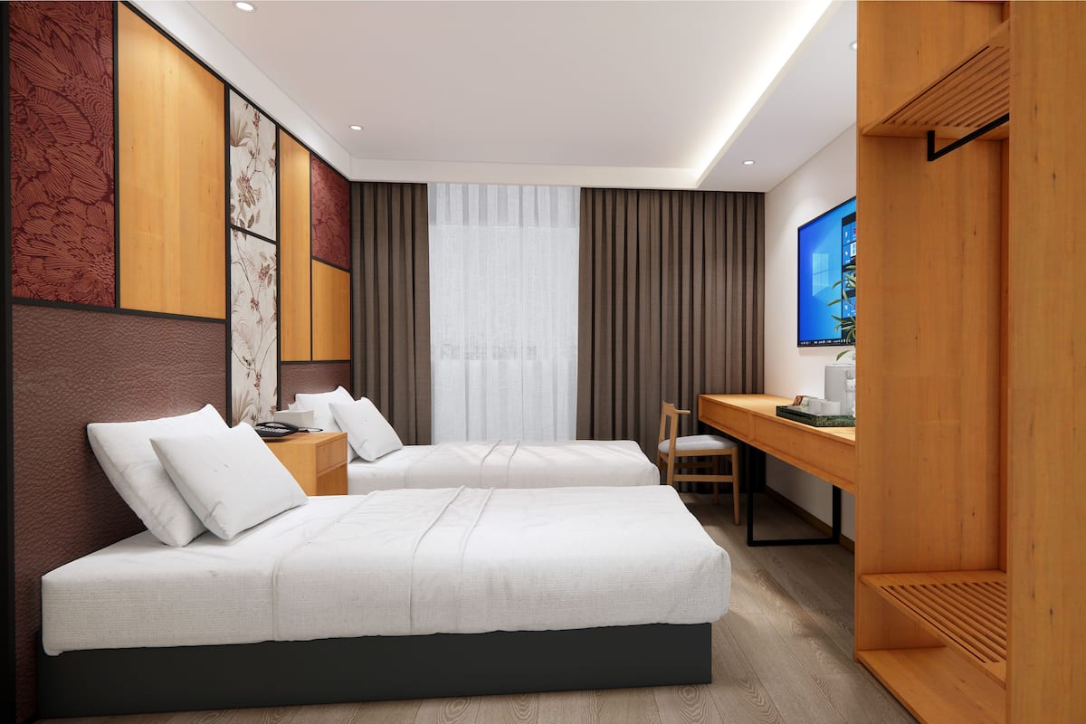 Quarto de hotel com duas camas, uma escrivaninha, uma cadeira e uma televisão.