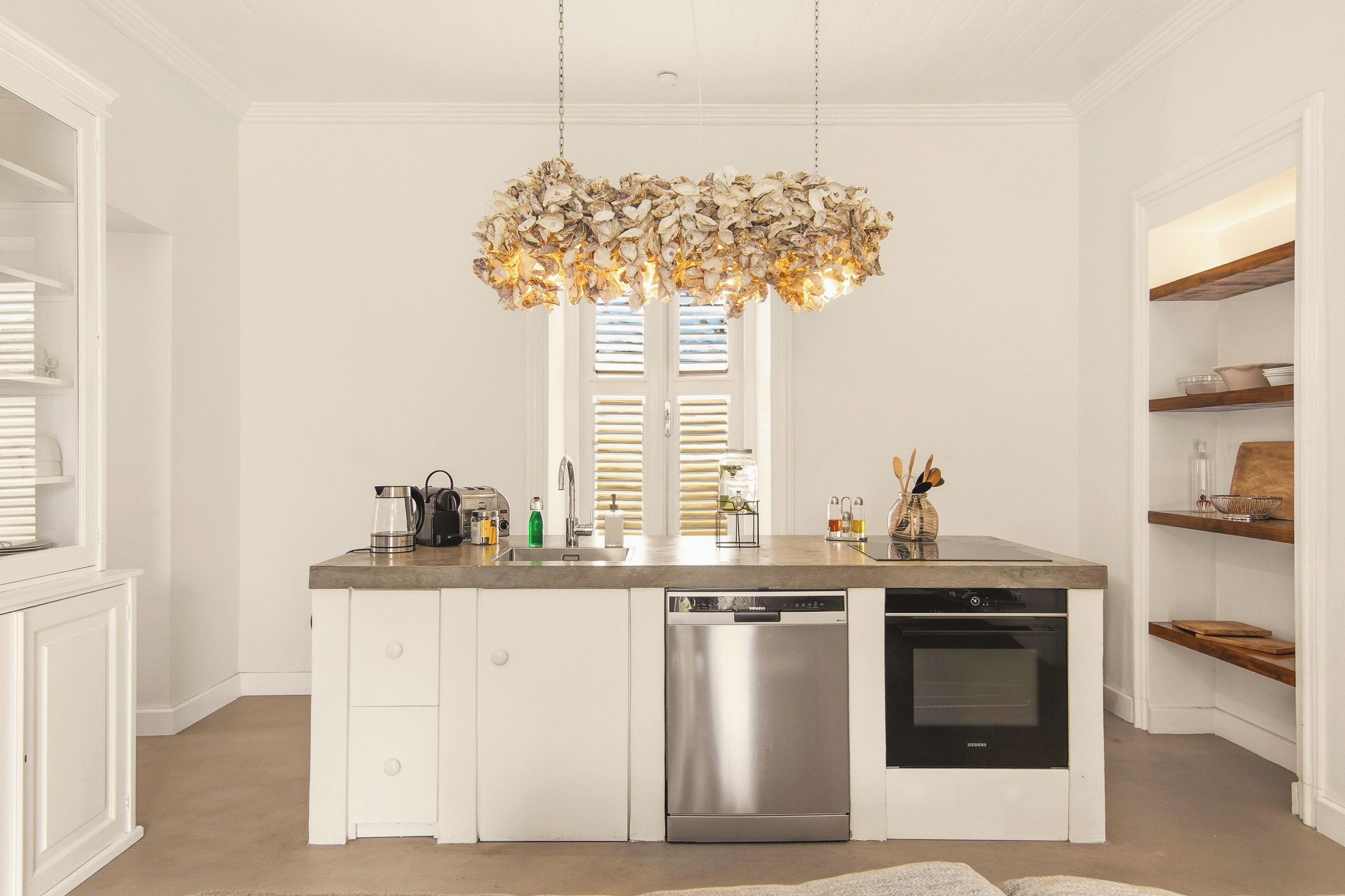 Een moderne keuken met een centraal eiland, roestvrijstalen apparatuur en een bijzondere kroonluchter.