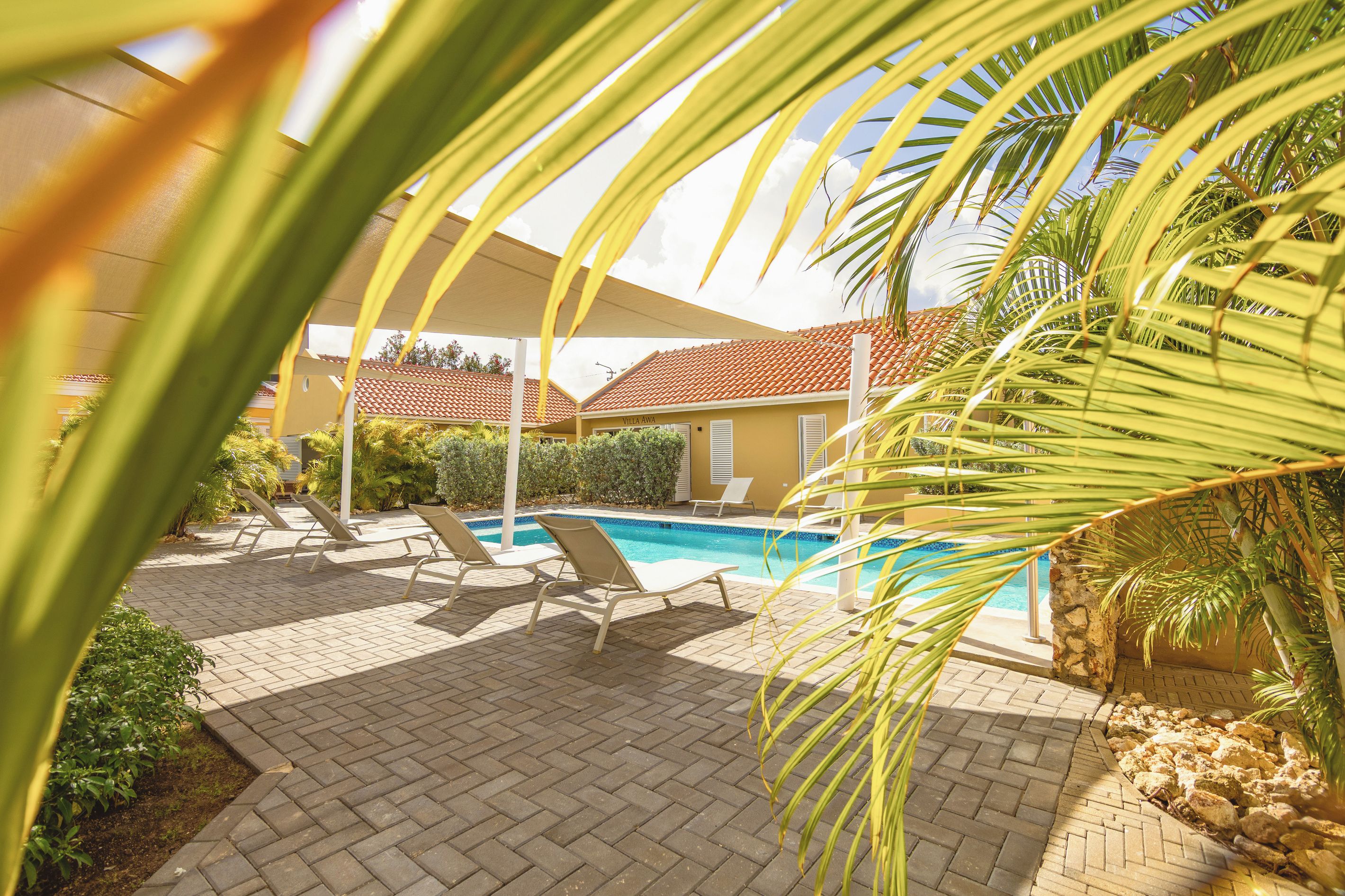 A pool area with lounge chairs, a tiled roof, and a building labeled 'Villa Awa'.