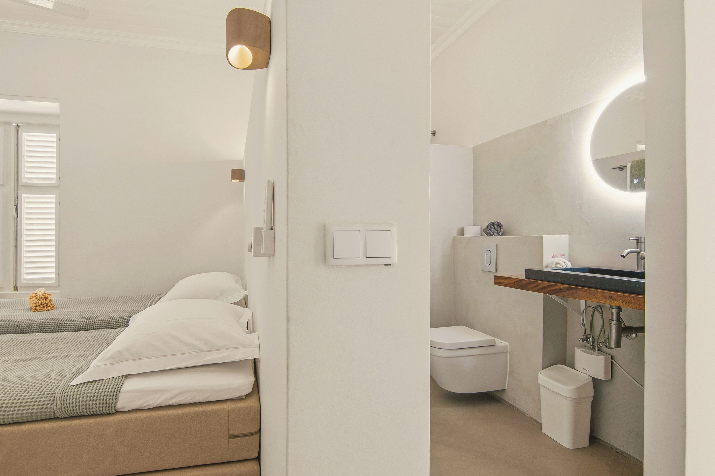 A modern bedroom with a bed, bedside tables, and a window with blinds.