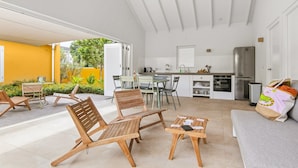 A modern kitchen with white cabinets, a stainless steel refrigerator, and a dining area with wooden chairs and a table. - Villa Grandi — three villas on one walled estate, for 16 guests in Otrobanda (Willemstad)