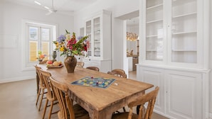A dining area with a wooden table, chairs, a vase of flowers, and a board game. - Villa Grandi — three villas on one walled estate, for 16 guests in Otrobanda (Willemstad)