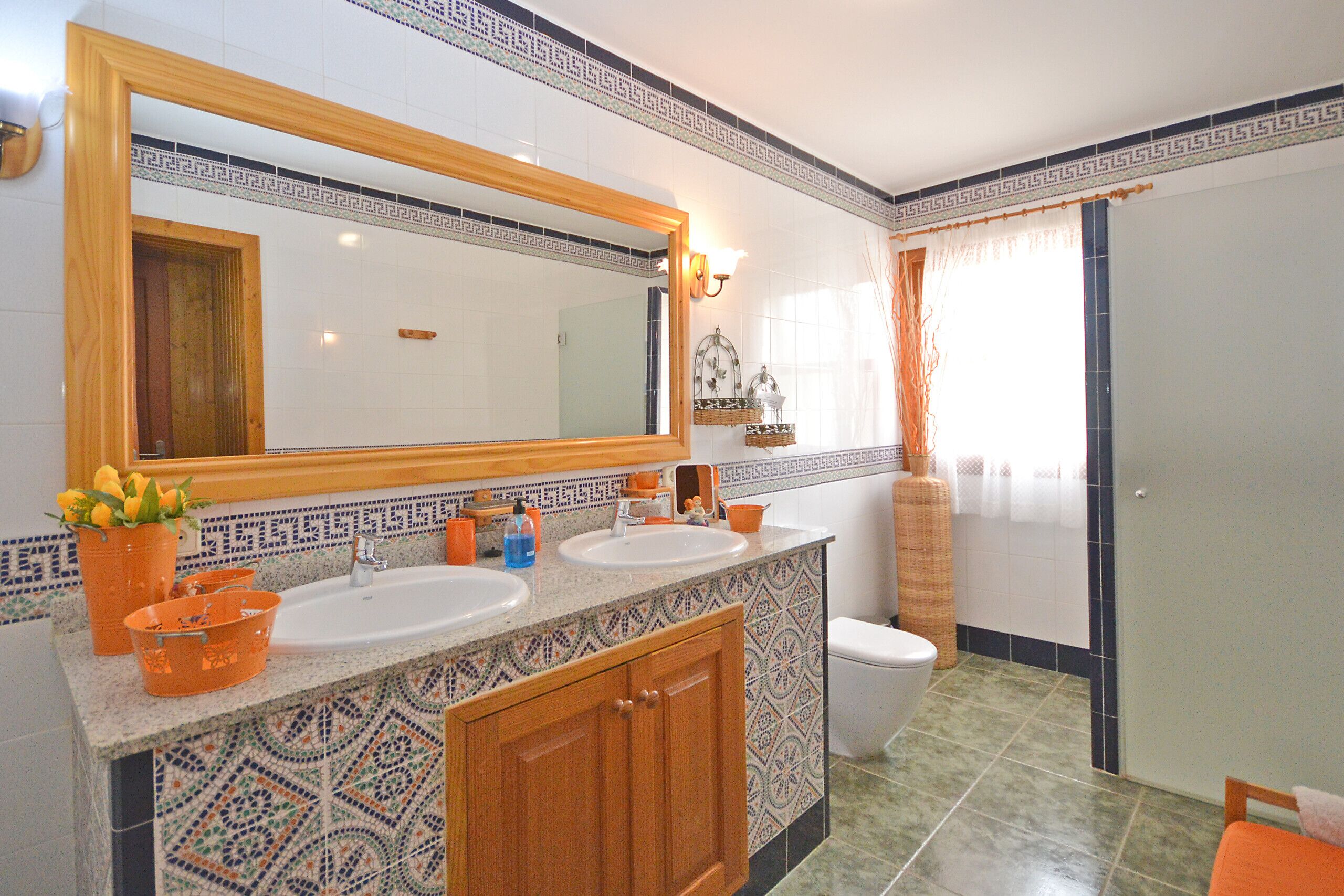 A bathroom with two sinks, a large mirror, and a toilet.