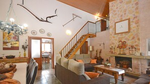 Uma sala de estar ampla com lareira, escada e área de jantar.