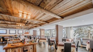 Un restaurante con techo de madera rústica, amplias ventanas y una zona de bar con diferentes botellas y vasos.