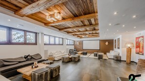 A spacious living area with a high ceiling, wooden beams, and a large window overlooking a snowy landscape. - Hotiday Sestriere Ski Run (Sestriere)