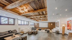 Un salón amplio con techo alto, vigas de madera y un gran ventanal.