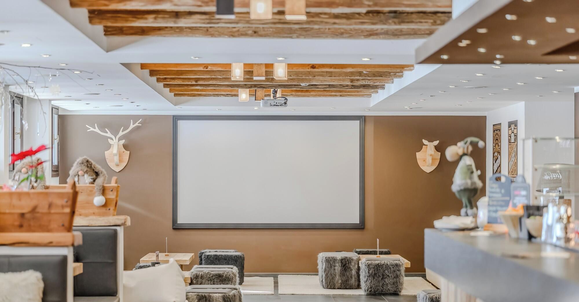 Un interior modern amb un gran pantalla, detalls de fusta i seients confortables.