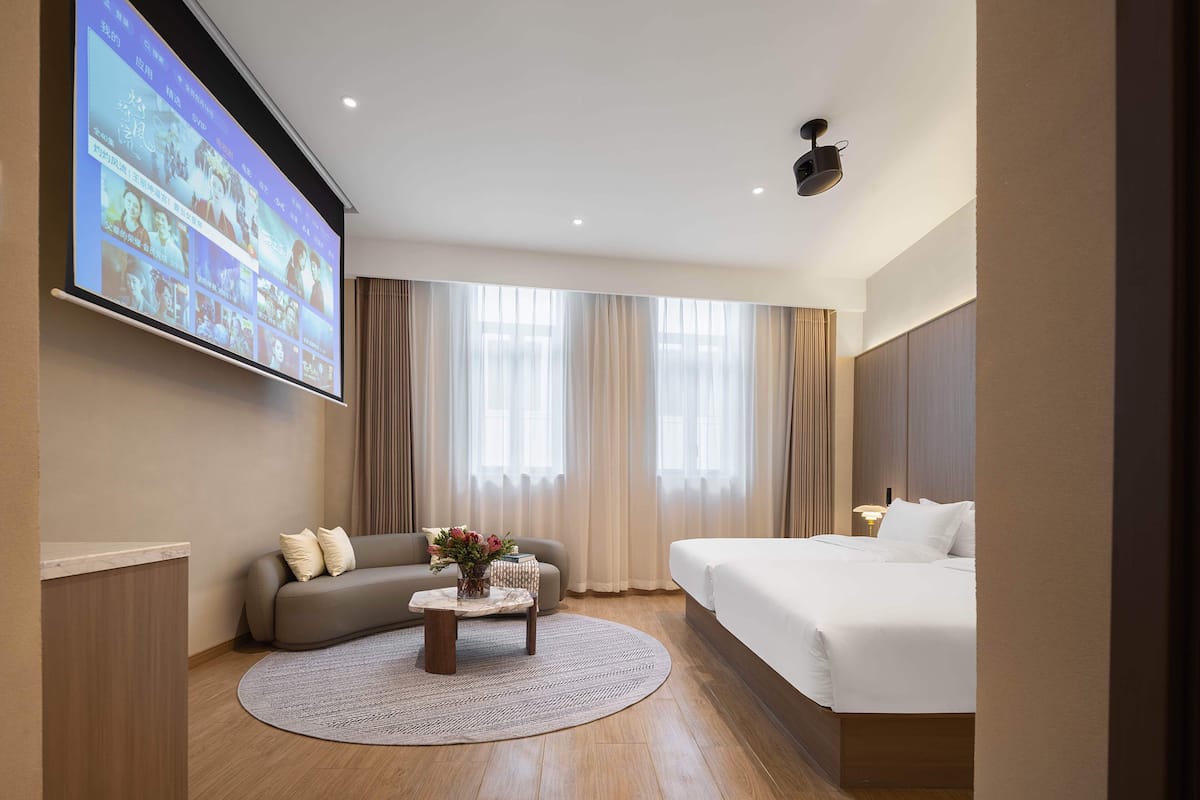 A hotel room with a bed, sofa, and a coffee table with flowers.