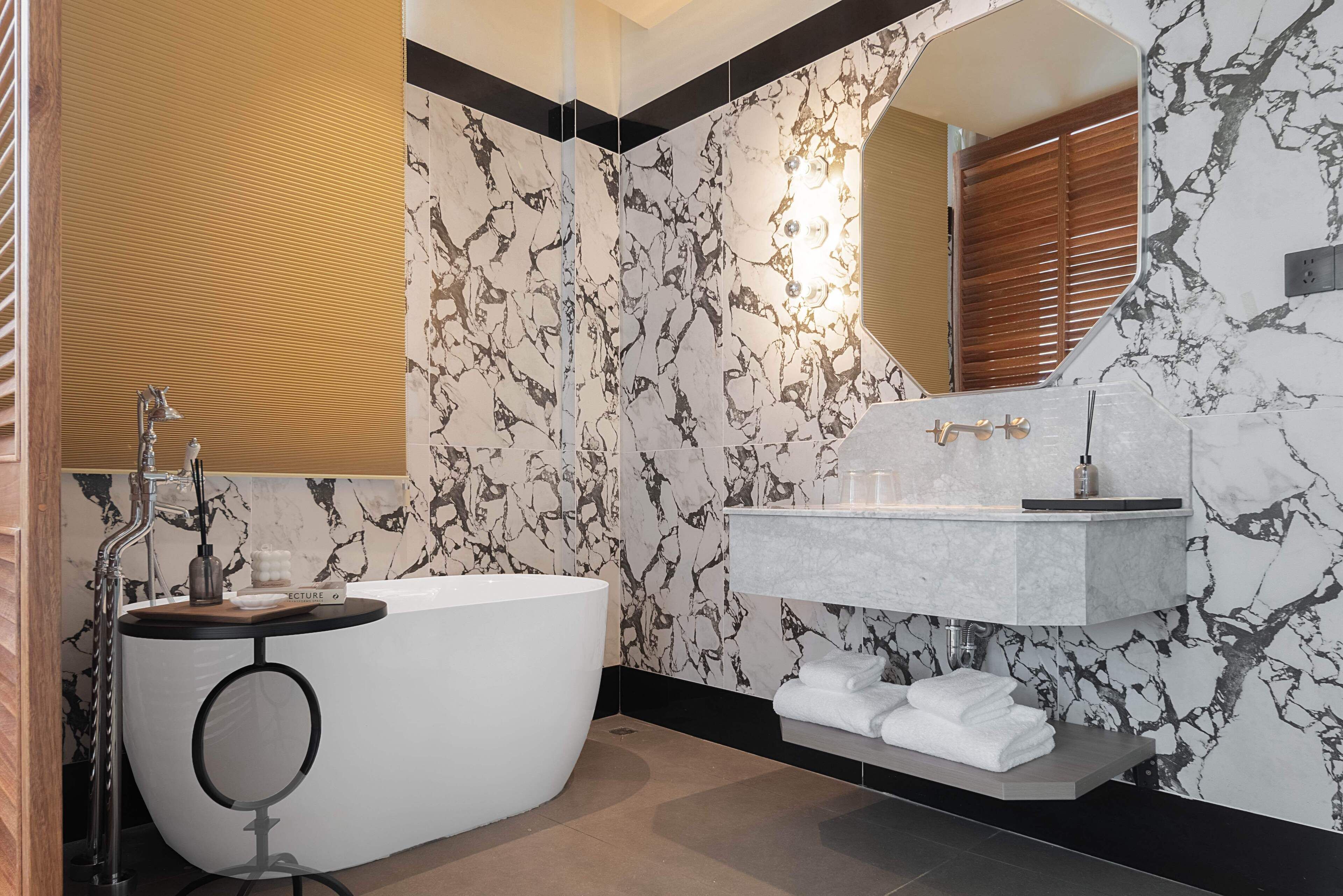 A modern bathroom with a freestanding bathtub, a vanity with a marble countertop, and a large mirror.