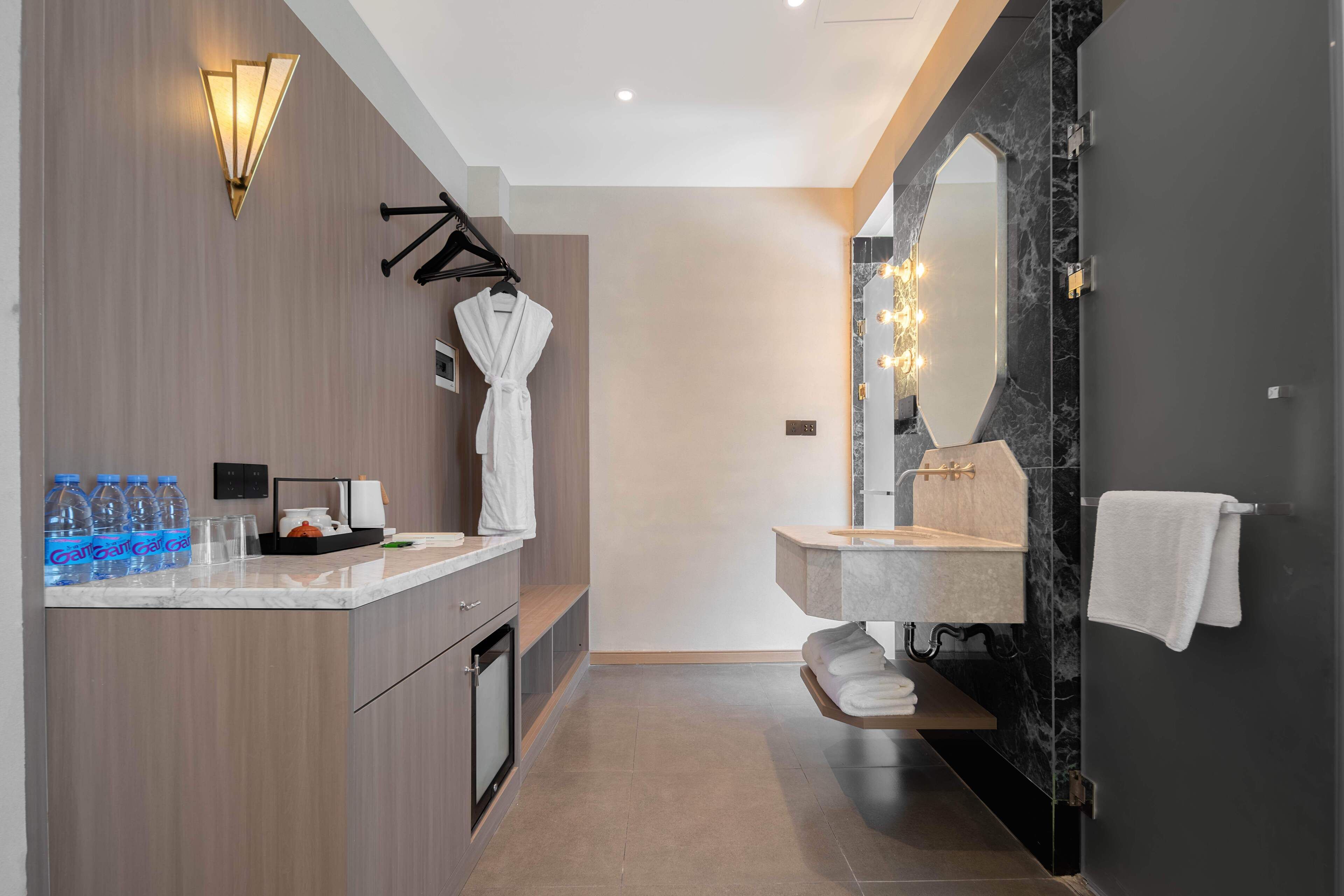 A modern bathroom with a vanity, a mirror with lights, a robe rack, and a towel rack.