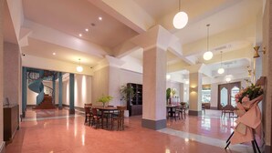 A spacious lobby with a central staircase, multiple seating areas, and a reception desk. - Mudita City Hotel (Xiamen)