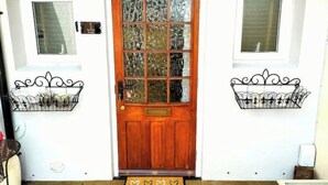 A wooden front door with a glass panel, flanked by two windows with metal railings.