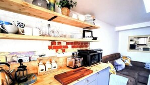 A kitchen with wooden shelves, a microwave, a toaster, and a coffee maker.