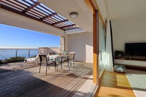 En balkon med et bord, stole, et fjernsyn og en stenvæg.
