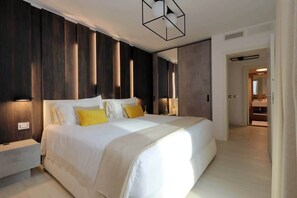 A modern bedroom with a large bed, bedside tables, and a walk-in closet.