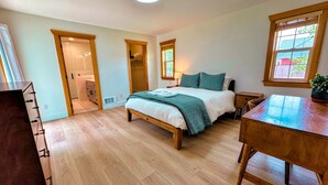 A bedroom with a wooden bed, a desk, and a window. There is a closet and a bathroom visible in the background. - Cozy 3BR/2BA Family Retreat in Driggs (Driggs)