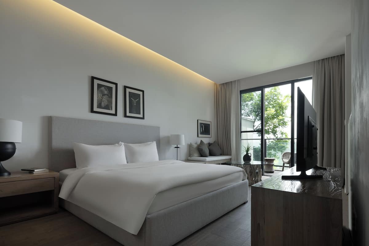 Ein modernes Hotelzimmer mit einem großen Bett, Nachttischen, einem Schreibtisch und einem Fernseher.