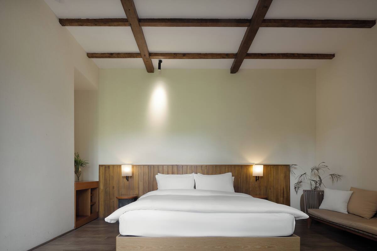Ein Schlafzimmer mit einem großen Bett, einem Holzkopfteil, Nachttischen und einem Beistelltisch.