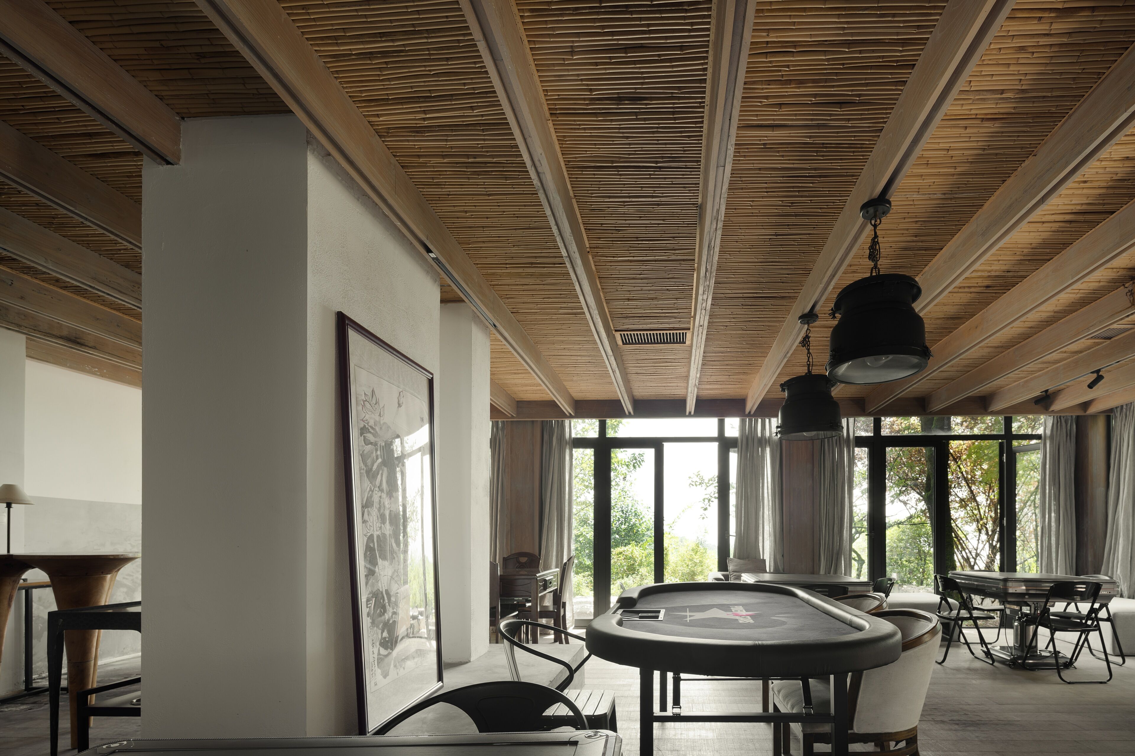 A modern interior with a wooden ceiling, large windows, and a billiards table.